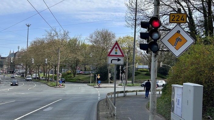 Straßenkreuzung mit roter Ampel, Verkehrsschildern und Gehweg an einer breiten Straße