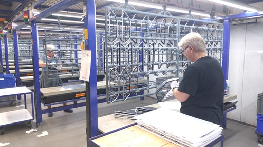 Zwei mittelalte Frauen in einer Industriehalle.
