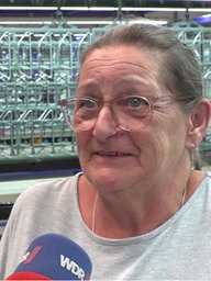 Eine Frau steht in einer Firmenhalle vor einem WDR-Mikrophon