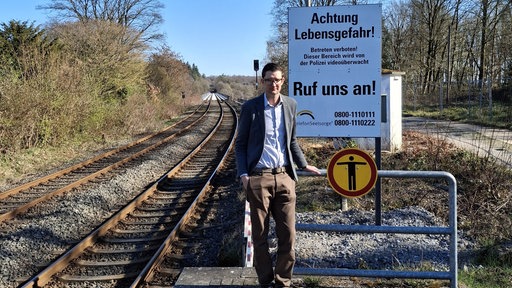 Fabian Christoph von der Bahntochter DB InfraGO vor dem Warnschild auf der Müngstener Brücke 
