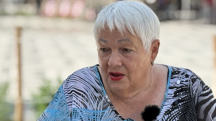 Frau mit kurzen weißen Haaren und blauem Oberteil
