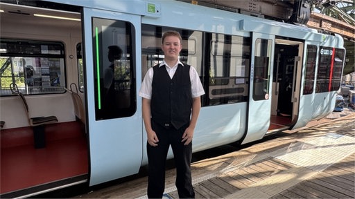 Nick Kaufmann steht vor der Schwebebahn