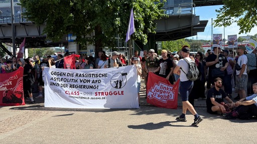 Gegendemonstranten halten Banner und Plakate gegen Rassismus und Hass hoch