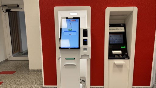 Bankautomat in Frontalansicht vor roter Wand
