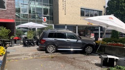 Großes graues Auto steht im Außenbereich einer Gastronomie