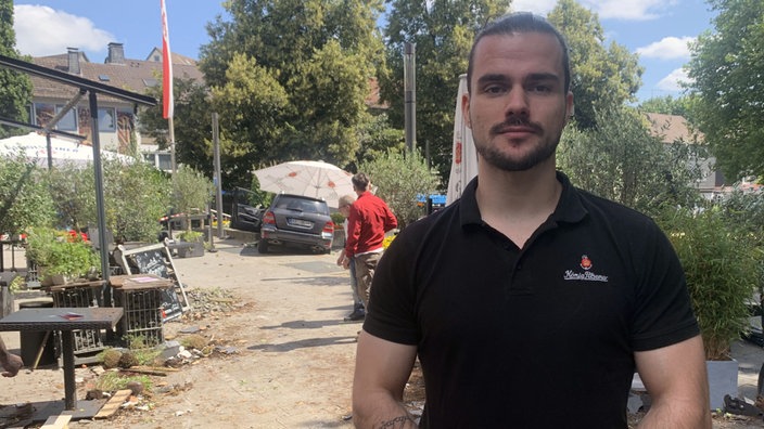 Barkeeper Jovan Janković steht vor dem verunfallten Auto in seiner Außengastronomie
