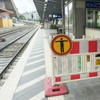 Das Bild zeigt einen Bahnsteig eines Bahnhofs, auf dem ein Bereich wegen Bau- oder Wartungsarbeiten abgesperrt ist.