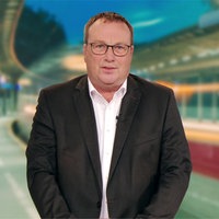 Ein Mann mit Brille steht vor einem Hintergrund, wo Bahnen zu sehen sind