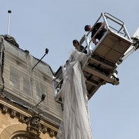 Bauarbeiterinnen mit einem Netz auf einem Kran.
