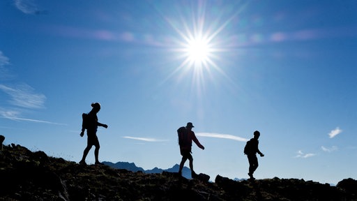Wuppertaler Bergsteiger auf einem Gipfel im Gegenlicht