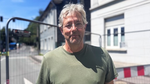 Ein Mann steht an einer abgesperrten Strasse