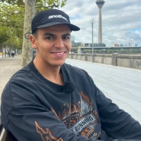 Ello sitzt auf einer Bank auf der Rheinpromenade