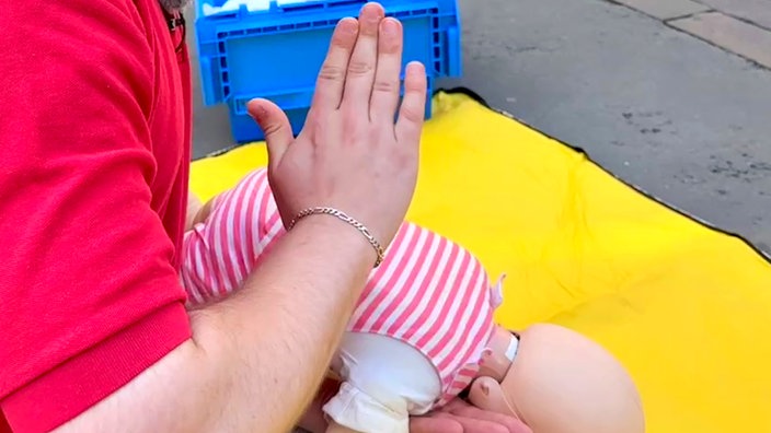Sanitäter klopft auf den Rücken einer Rettungspuppe