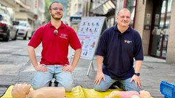 Ein Sanitäter erklärt einem Interessenten die Rettungspuppe