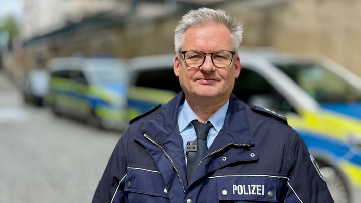 Polizeisprecher vor Streifenwagen