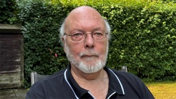 Ein Mann mit weißen Haaren und Brille