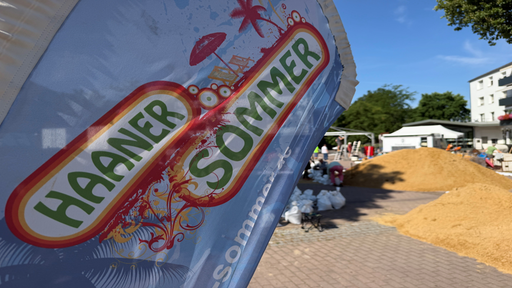 Banner mit der Aufschrift "Haaner Sommer" steht im Vordergrund, dahinter sieht man ein Gelände, auf dem Sandberge liegen