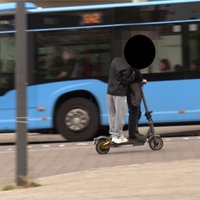 Zwei Fahrer auf einem E-Scooter dahinter ein fahrender Bus