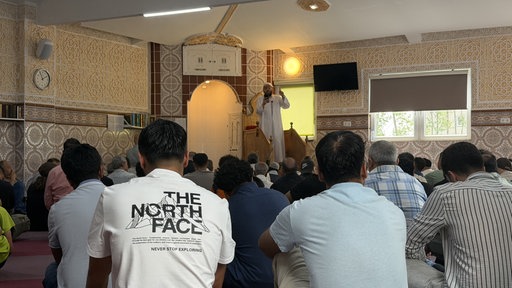 Männer sitzen in einer Moschee.