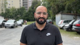 Ismael steht auf einem Parkplatz.