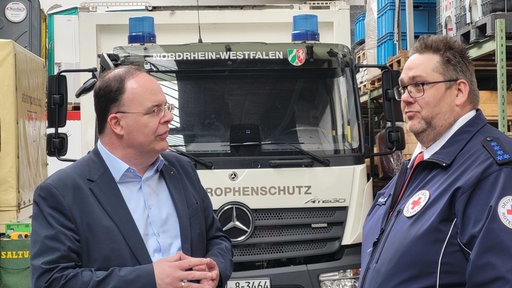 zwei Männer unterhalten sich vor einem Katastrophenschutz Wagen