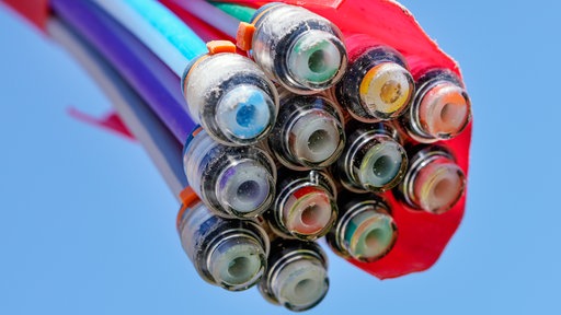 Bunte Glasfaserkabel ranken vor einem blauen Himmel ins Bild