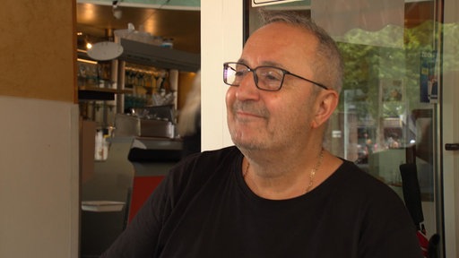 Ein Mann mit Brille lächelt zufrieden