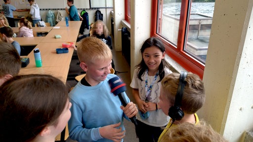 Kinder in einem Klassenzimmer interviewen sich gegenseitig.