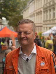 Mann mit orangener Jacke