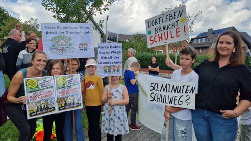 Kinder demonstrieren mit selbstgebastelten Schildern.