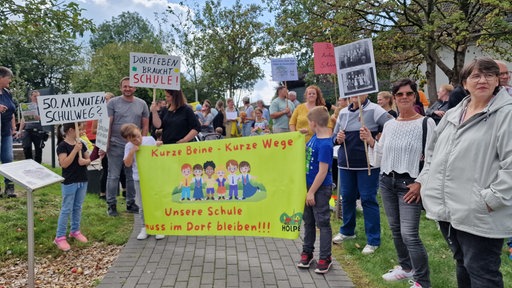 Kinder und Erwachsene demonstrieren mit selbst gebastelten Schildern.