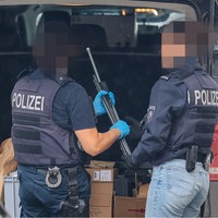 zwei Polizisten holen ein Gewehr aus dem Kofferraum