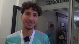 Ein junger Mann mit dunklen Locken lacht
