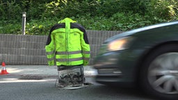 Ein Dummy mit gelber Warnjacke wird gerade von einem Auto erfasst