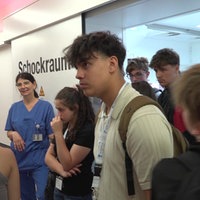 Junge Menschen und eine Pflegekraft stehen vor und im Eingang eines Schockraums