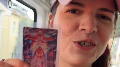 Lara mit einer Pokemon-Karte in der Schwebebahn