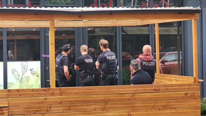 Vier Personen in Polizeibekleidung stehen vor einer Glastür bzw. Fensterfront. Auf den Westen bzw. der Kleidung ist  „POLIZEI“ zu lesen, eine Person trägt zusätzlich die Aufschrift „Kriminaltechnik“ auf dem Rücken.