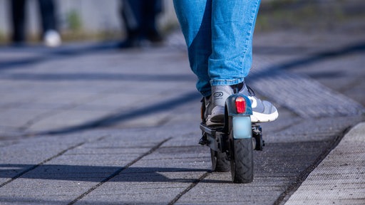 Mensch steht auf einem E-Scooter