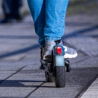Mensch steht auf einem E-Scooter