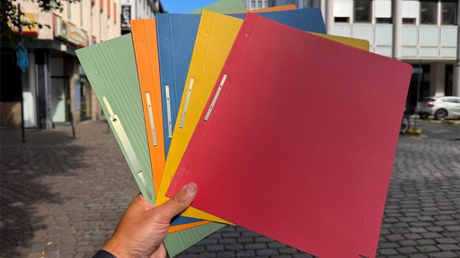 Hand hält bunte Hefter