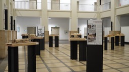 In einem Museum ist eine Ausstellung mit mehren kleinen Bahnhofsmodellen zu sehen. 