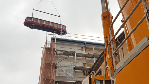 der historischer Schwebebahnwagen wird von einem Kran transportiert
