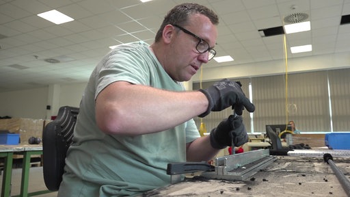Ein Mann mit Brille arbeitet in einer Werkstatt