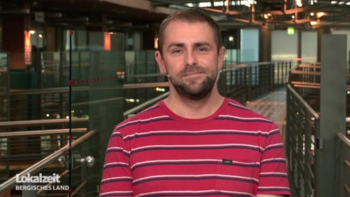 Mann im roten T-Shirt schaut in die Kamera