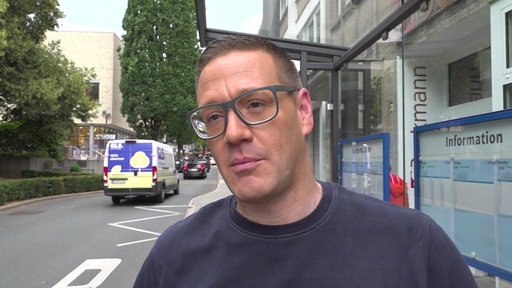 Ein Mann an einer Bushaltestelle gibt ein Interview