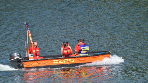 Rettungsschwimmer suchen mit einem Schlauchboot nach Vermissten