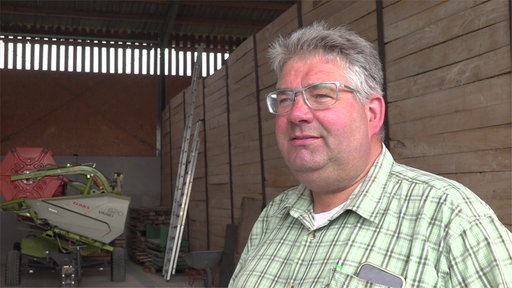 Ein Mann mit grauen Haaren in einem grün-karrierten Hemd schaut links neben der Kamera vorbei