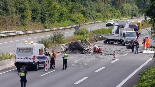 Unfall auf der A46, ein Auto wird gerade vomm Abschleppdienst abgeschleppt, Polizisten und weitere Menschen stehen auf der gesperrten Fahrbahn.