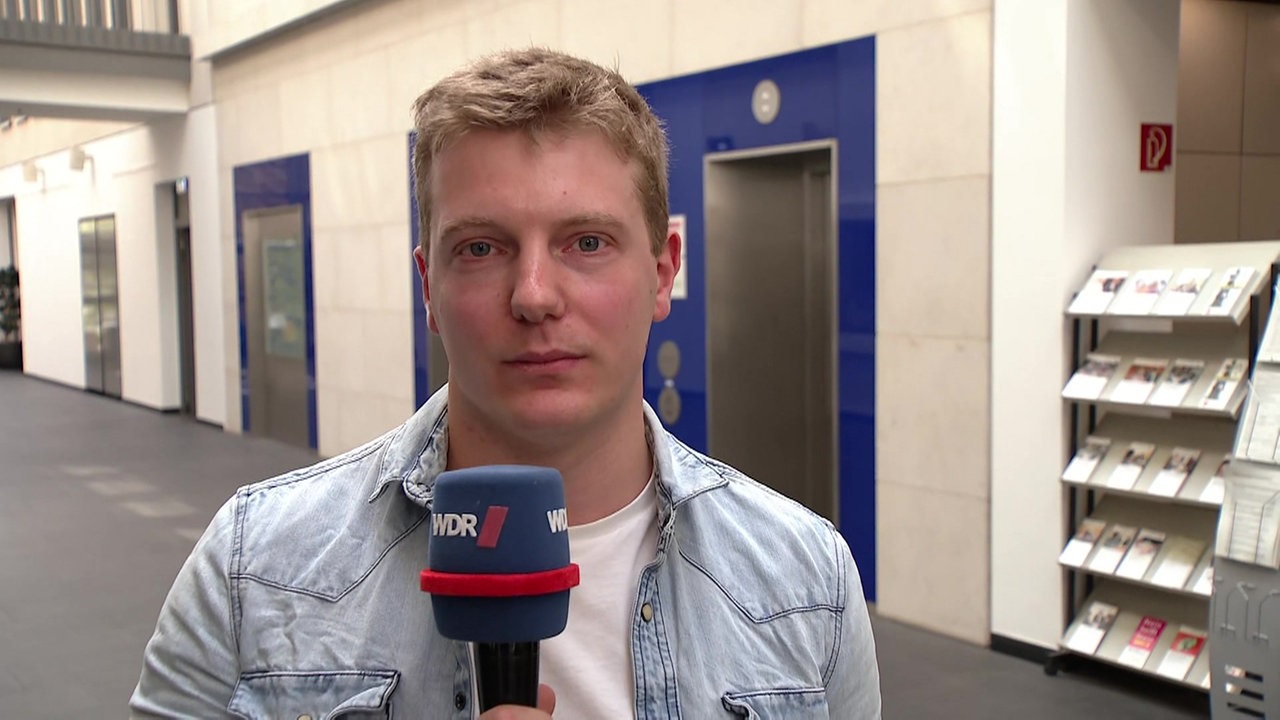 WDR Reporter Benny Degen steht mit Mikrofon im Landgericht Wuppertal