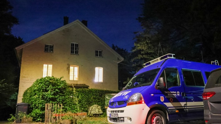 Ein Fahrzeug des THW vor einem Haus. Es ist nachts.